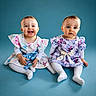Ilyanna Et Ayanna a rejoint le concours — aidez-le/la à gagner de superbes lots ! baby, blue_background, butterfly, child, colorful_clothing, cute, dress, happy, indoor, infant, playful, portrait, short_hair, sitting, smile, studio_photo, toddler, two_children, white_tights, young