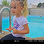 blonde_hair, braided_hair, calm, casual_clothing, child, curly_hair, daytime, earrings, fashion, fence, nike_logo, outdoor, pool, portrait, residential_area, sitting, trees, white_tshirt, wooden_deck, young_girl