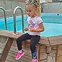 child, pool, outdoor, braided_hair, pink_sneakers, wooden_structure, concrete_wall, blue_pool, cloudy_sky, casual_clothing, sitting, young_child, thoughtful, residential_area, ladder, sporty, nike, curly_hair, daytime, calm