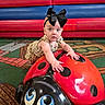 Kelsi is registered to the contest to win money with this photo: baby, child, bow, indoor, play_area, ladybug, sculpture, toy, carpet, colorful, padded_bench, red, blue, curious, crawling, person, face, hand, clothing, floor
