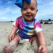 Kelsi is registered to the contest to win money with this photo: baby, child, sand, beach, smiling, colorful_clothing, bow, headband, outdoor, sunny, sky, people_in_background, happy, sitting, footwear_free, portrait, infant, summer, vacation, playful