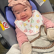 Jasmine joined the competition — help win amazing prizes! baby, infant, smile, car_seat, headband, bow, bib, blanket, mittens, clothing, face, person, cute, happy, indoors, child, warm, seat, fabric, texture
