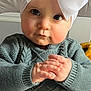 baby, infant, headband, bow, chubby_cheeks, big_eyes, sweater, knitwear, hands_clasped, portrait, close_up, indoors, crib, cute, expression, skin, hair, seat, blanket, toy