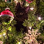 black_cat, christmas_tree, christmas_ornament, snowflake_ornament, christmas_lights, holiday_decor, festive, greenery, pet, animal, curious, indoor, closeup, celebration, seasonal, decor, cute, tree_branch, ornament, night