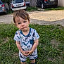 Owenn participe au concours pour gagner de l'argent avec cette photo : blue_eyes, casual, child, clothing, concrete_wall, curious, daylight, expression, footwear, grass, greenery, hair, nature, outdoor, parked_cars, patterned_clothing, person, shorts, standing, toddler