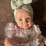 baby, infant, child, blue_eyes, headband, bow, pink_dress, frills, flower, beads, hand, soft_texture, brown_background, portrait, cute, young_child, laying_down, close_up, clothing, smile