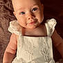 Lily is registered to the contest to win money with this photo: baby, infant, child, blue_eyes, white_dress, lace, smile, face, soft_skin, portrait, closeup, cute, lying_down, blanket, fabric, innocence, adorable, human, young, person