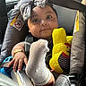 Ivey joined the competition — help win amazing prizes! baby, child, car_seat, seatbelt, headband, bow, sock, foot, plush_toy, yellow_toy, bracelet, happy, smiling, indoors, car_interior, cute, infant, person, closeup, safety