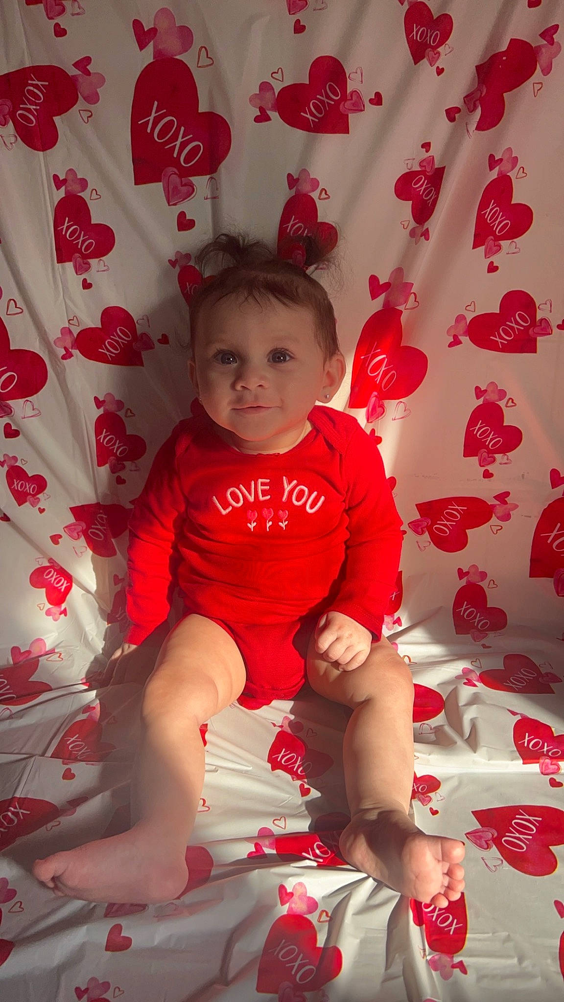 Gianna is registered to the contest to win money with this photo: baby_toddler_clothing, carmine, curtain, event, foot, happy, holiday, human_leg, lap, leg, magenta, pattern, person, pink, red, sitting, sleeve, sock, thigh, toddler
