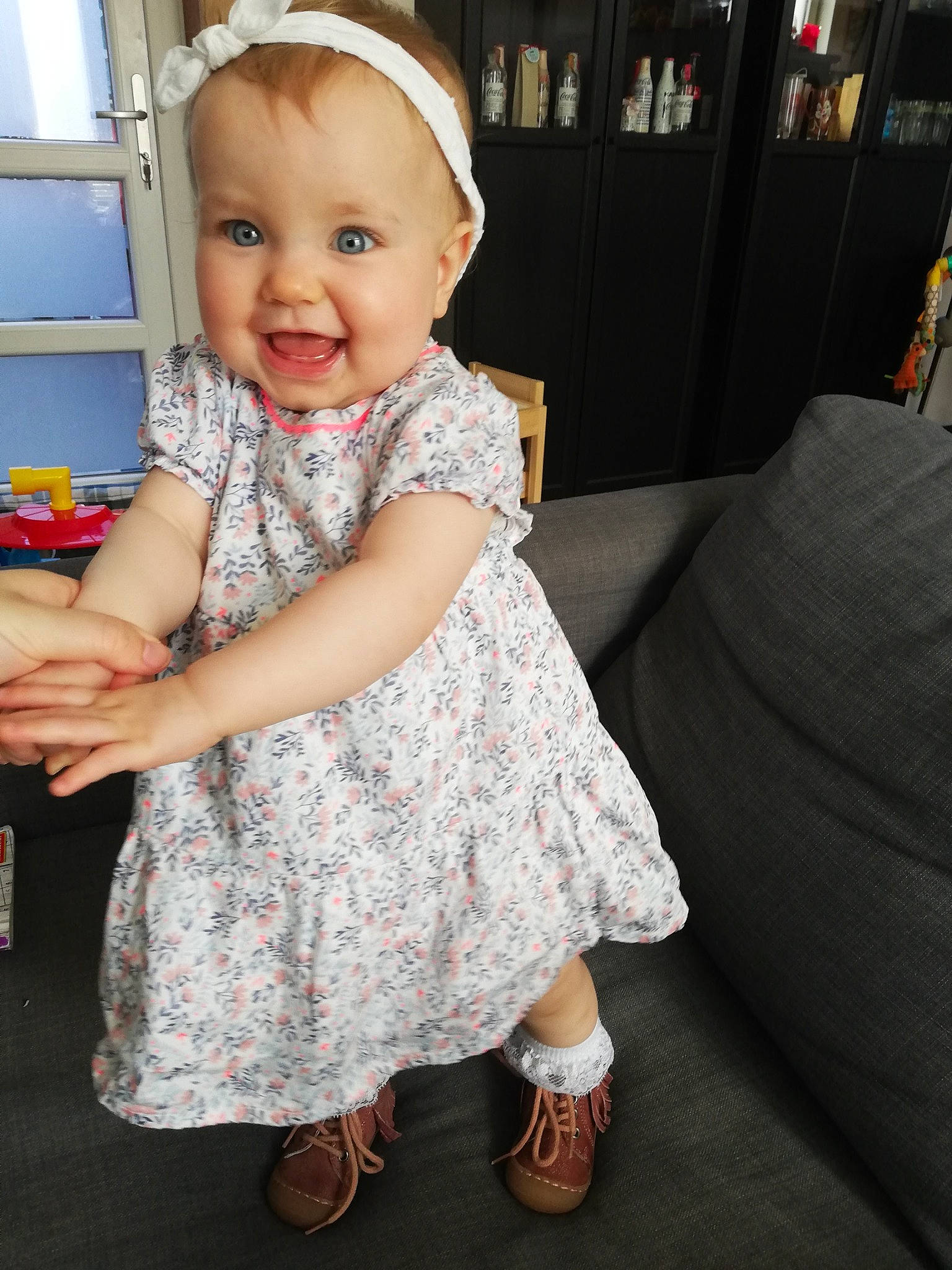 Flore a rejoint le concours — aidez-le/la à gagner de superbes lots ! baby, baby_toddler_clothing, child, dress, facial_expression, flooring, foot, fun, hairstyle, happy, iris, pattern, person, pink, sandal, skin, sleeve, smile, standing, toddler