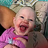 baby, infant, child, laughing, smiling, portrait, close_up, indoor, caregiver, adult, tattoo, pink_shirt, purple_clothing, hands, cuddling, blanket, bedroom, patterned_background, happy, family