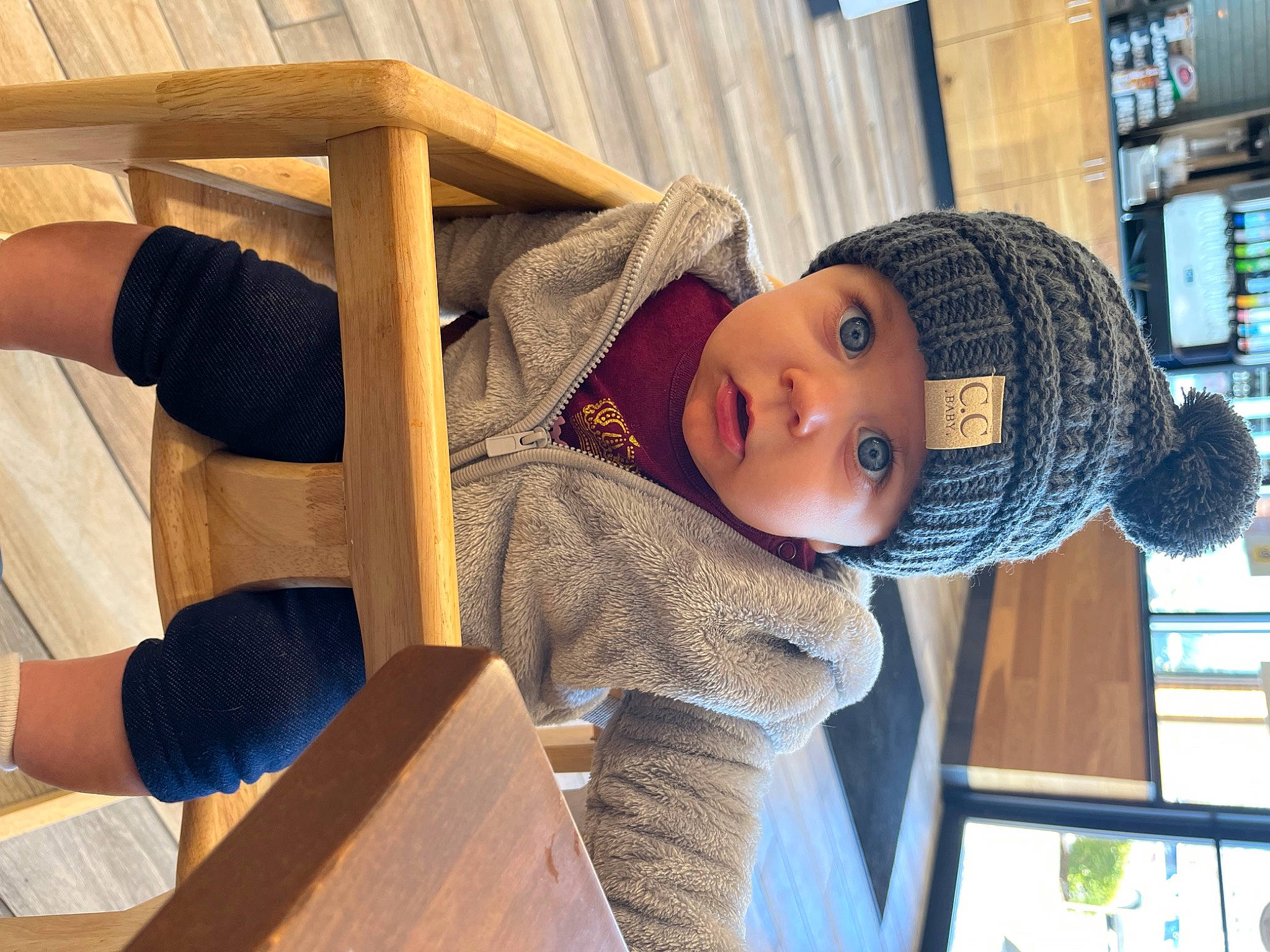 Sera joined the competition — help win amazing prizes! baby, baby_toddler_clothing, beanie, cap, child, comfort, electric_blue, flooring, hardwood, hat, headwear, knit_cap, leisure, person, sitting, toddler, tree, window, wood, wood_stain