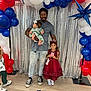 Penelope joined the competition — help win amazing prizes! man, baby, child, balloons, red_dress, silver_backdrop, floor, smiling, party, celebration, headband, shoes, casual_clothing, indoor, floor_mark, family, holding, posing, decorations, event