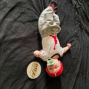 Silas joined the competition — help win amazing prizes! baby, infant, pacifier, clothing, red_hat, white_onesie, grey_pants, black_blanket, wooden_sign, one_month, lying_down, indoors, cute, milestone, child, portrait, baby_clothes, headwear, soft_texture, small_hands