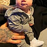 Silas joined the competition — help win amazing prizes! baby, child, infant, grey_tracksuit, beanie, white_sneakers, tattooed_hands, portrait, indoor, cute, sitting, clothing, footwear, person, headwear, expression, soft_lighting, blurred_background, casual, cozy