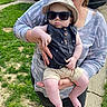 baby, child, woman, sunglasses, hat, outdoor, grass, car, sidewalk, holding, casual_clothing, smiling, person, sunny, summer, cute, portrait, fashion, accessory, family