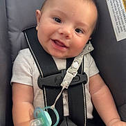 Brendon is registered to the contest to win money with this photo: baby, smiling, car_seat, pacifier, infant, child, safety_harness, clothing, cute, hands, head, face, seat_belt, indoor, young_child, happy, expression, blanket, strap, person