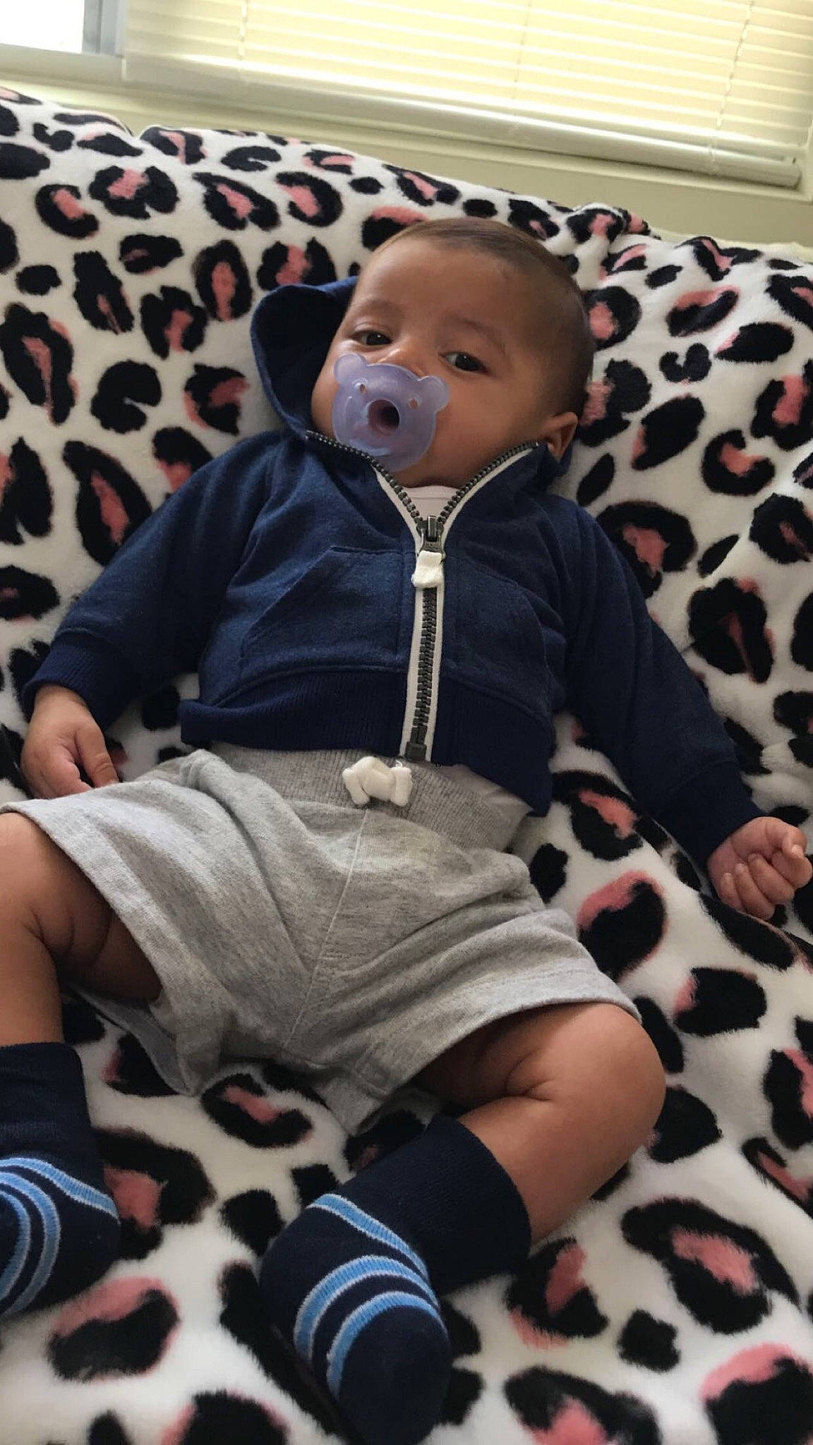 Omar is registered to the contest to win money with this photo: baby, baby_toddler_clothing, black, clothing, comfort, face, facial_expression, head, knee, lap, leg, mammal, outerwear, person, product, skin, sleeve, sock, thigh, toddler
