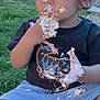 Keion is registered to the contest to win money with this photo: black_tshirt, cake, child, cream, dinosaur_print, eating, face, food, grass, hands, happy, messy, nature, outdoor, playful, shorts, sitting, summer, sunny, toddler