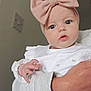 baby, child, infant, headband, pink_bow, blue_eyes, white_clothing, hand, adult_arm, portrait, indoor, curious, cute, person, face, skin, sleeve, closeup, soft_light, neutral_background