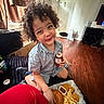 Elijah joined the competition — help win amazing prizes! child, toddler, smiling, curly_hair, portrait, indoor, sitting, food, burger, french_fries, chicken_nuggets, dipping_sauce, drink, casual_clothing, gray_shirt, red_foreground, wooden_floor, living_room, candid_photo, happy