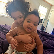 Elijah is registered to the contest to win money with this photo: children, baby, toddler, siblings, cuddling, hugging, smiling, portrait, indoors, bedroom, bed, blanket, curly_hair, infant, diaper, family, affection, cozy, window, natural_light