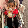 Unique joined the competition — help win amazing prizes! baby, child, infant, high_chair, bottle, feeding, milk, red_shirt, black_pants, barefoot, sitting, indoors, carpet, toy, pink_chair, safety_harness, portrait, looking_at_camera, dark_hair, face