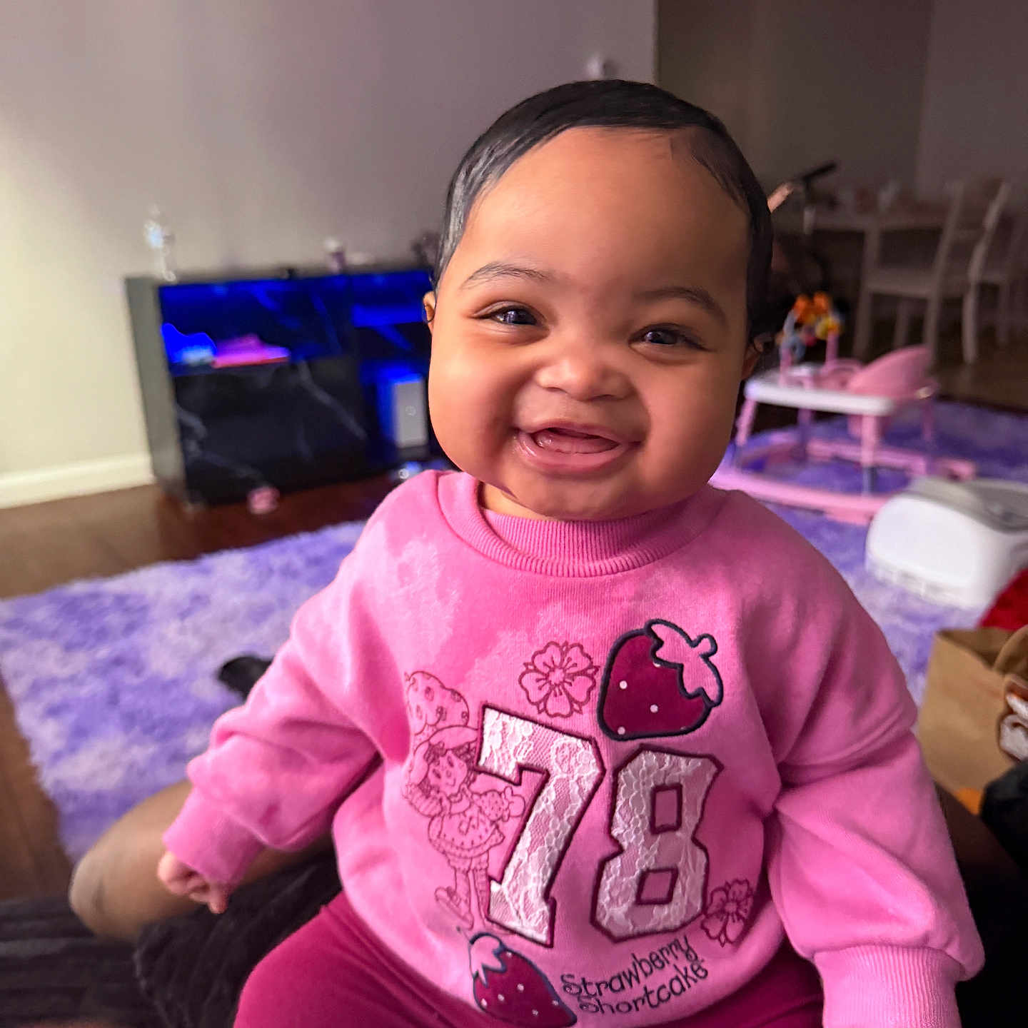 Unique joined the competition — help win amazing prizes! baby, child, infant, smiling, happy, portrait, indoor, living_room, pink_clothing, sweater, strawberry, number_78, aquarium, fish_tank, play_center, rug, seated, home, close_up, family_photo