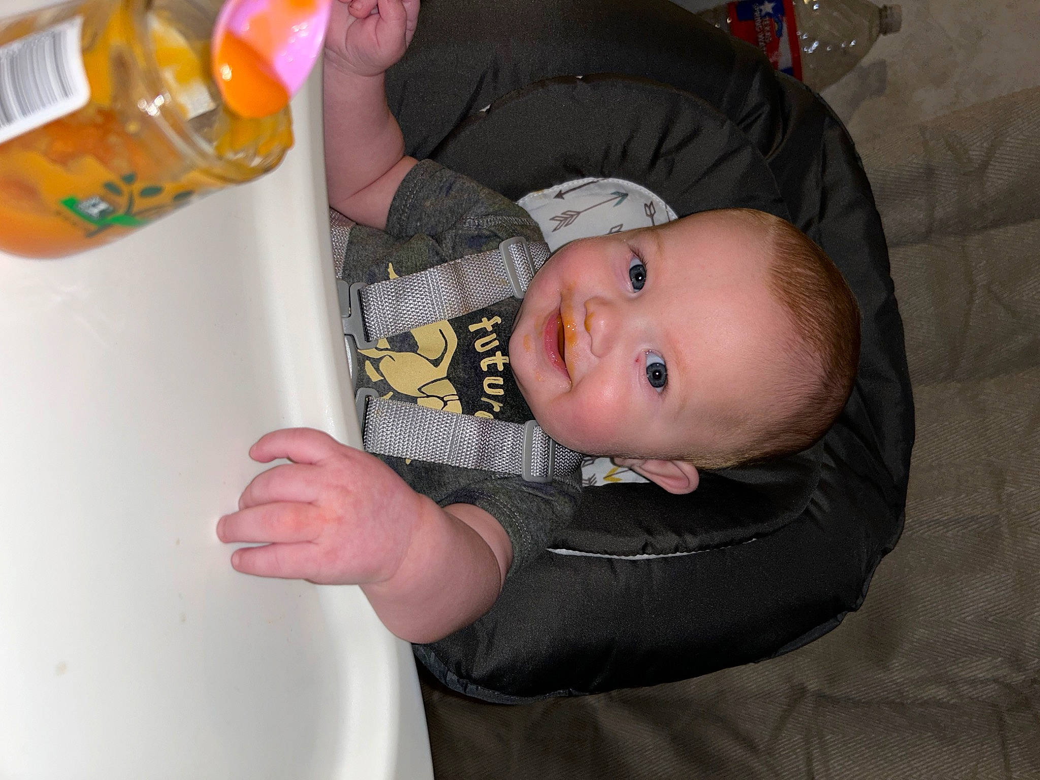 Reed is registered to the contest to win money with this photo: baby, baby_products, baby_toddler_clothing, bottle, child, drinkware, finger, fun, joy, person, plastic, plastic_bottle, room, sitting, smile, toddler, water_bottle, wood