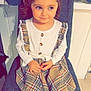 child, girl, pigtails, plaid_dress, white_tights, black_boots, chair, indoor, smile, cute, sitting, long_sleeve_shirt, buttons, hands, floor, wall, furniture, portrait, young_child, happy