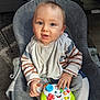 baby, child, infant, toy, game_controller, striped_clothing, bib, sitting, gray_chair, indoor, carpet, curious, blue_eyes, hand, face, smiling, young, cute, person, home