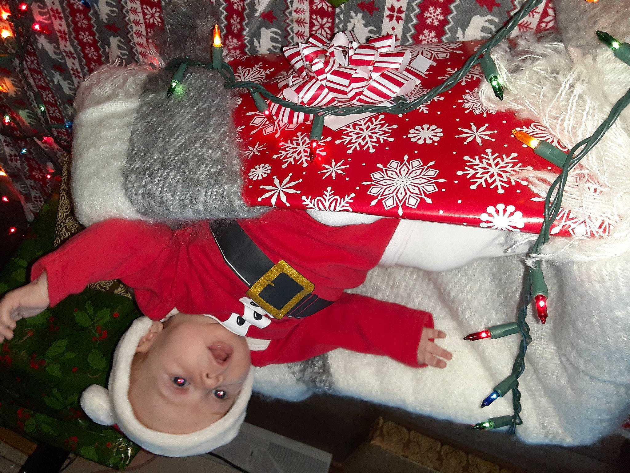 Azariah is registered to the contest to win money with this photo: baby_toddler_clothing, bag, carmine, christmas, christmas_decoration, christmas_eve, christmas_ornament, christmas_tree, event, fashion_accessory, fictional_character, fur, happy, holiday, lap, person, product, red, sleeve, snapshot