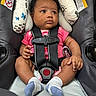 Zsamiya is registered to the contest to win money with this photo: baby, infant, car_seat, child, curly_hair, pink_onesie, socks, harness, seat_belt, warning_label, black_harness, cute, indoor, portrait, seated, safety, car_safety, hands, legs, expression