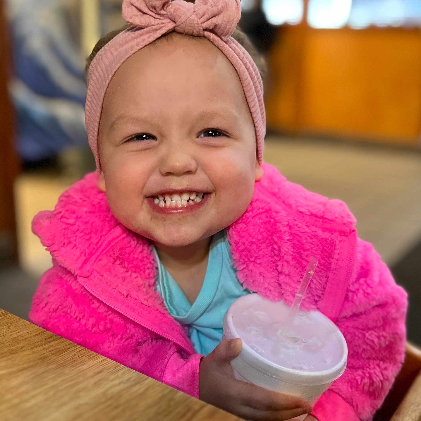 Brighton joined the competition — help win amazing prizes! child, clothing, cup, cute, drink, face, furniture, happy, headband, holding, indoor, person, pink_jacket, portrait, smiling, table, toddler, warm_clothing, wood, young_child