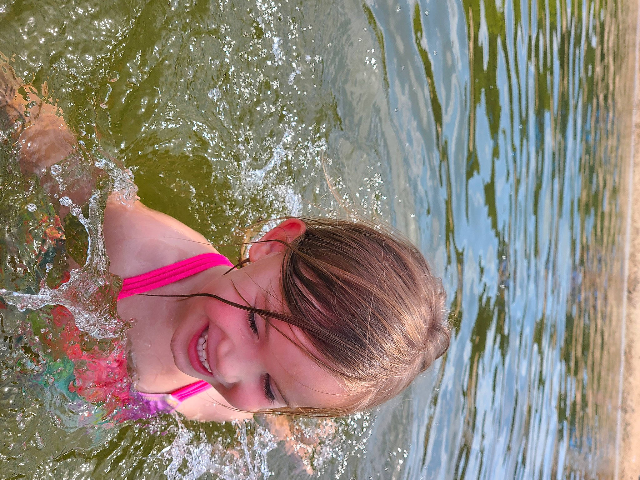 Lilian is registered to the contest to win money with this photo: bathing, child, face, fun, grass, hair, happy, head, joy, lake, leisure, people_in_nature, person, plant, recreation, smile, summer, sunglasses, swimwear, toddler