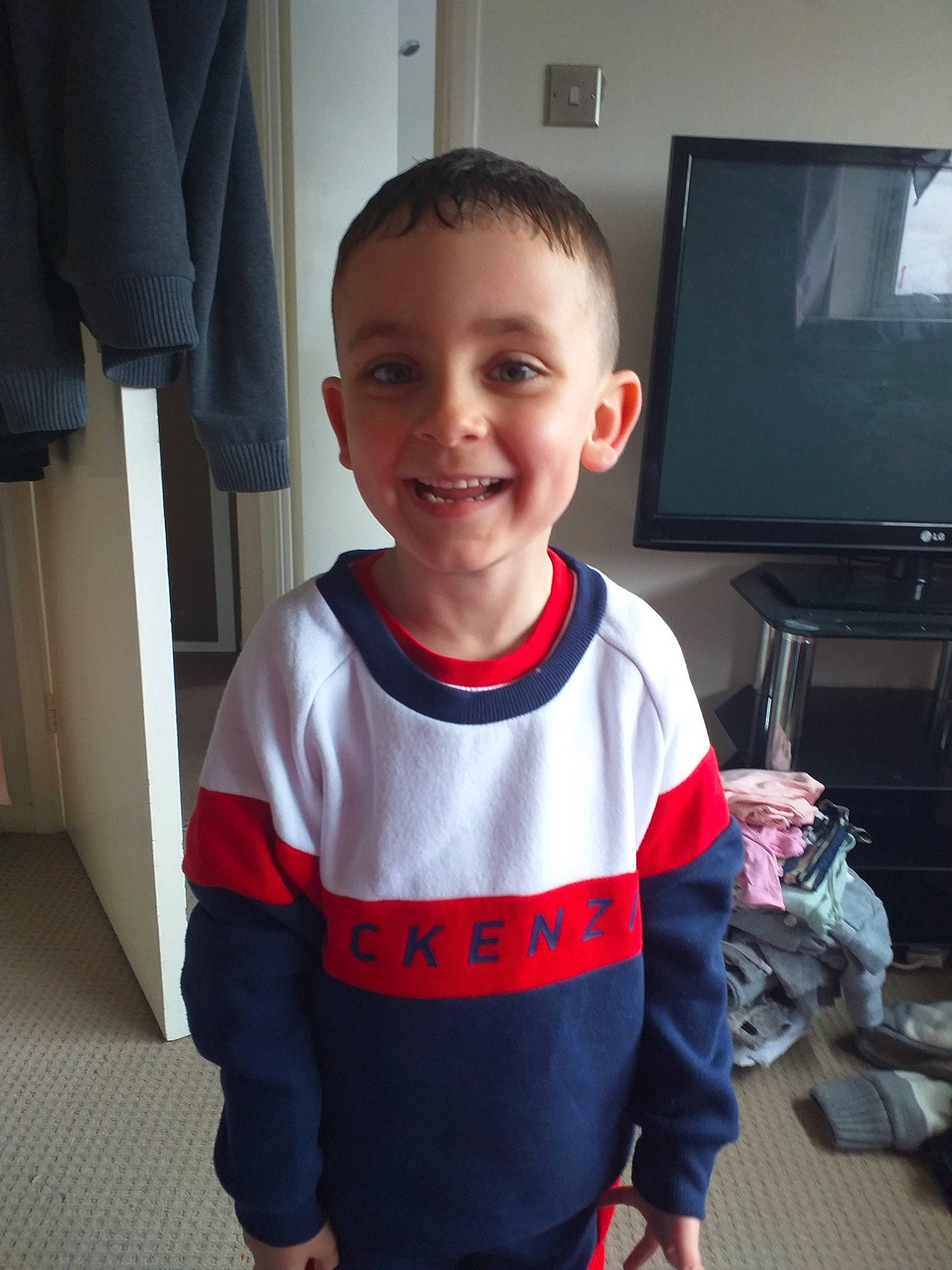 Ryan is registered to the contest to win money with this photo: cheek, child, face, facial_expression, fictional_character, head, joy, male, person, personal_protective_equipment, shoulder, skin, sleeve, smile, standing, t_shirt, toddler, tooth