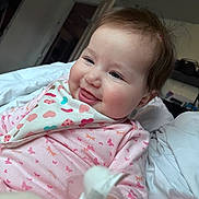 Mary joined the competition — help win amazing prizes! baby, child, smiling, pink_clothing, bib, bed, blanket, indoor, cute, face, happy, infant, person, portrait, sleepwear, butterfly_pattern, head, hair, skin, closeup