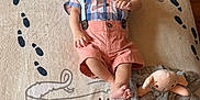 Antony Romeo is registered to the contest to win money with this photo: baby, infant, smiling, plush_toy, blanket, floor, wood_floor, child, clothing, bow_tie, suspenders, toy, soft_toy, cute, lying_down, happy, face, footwear, indoors, playful