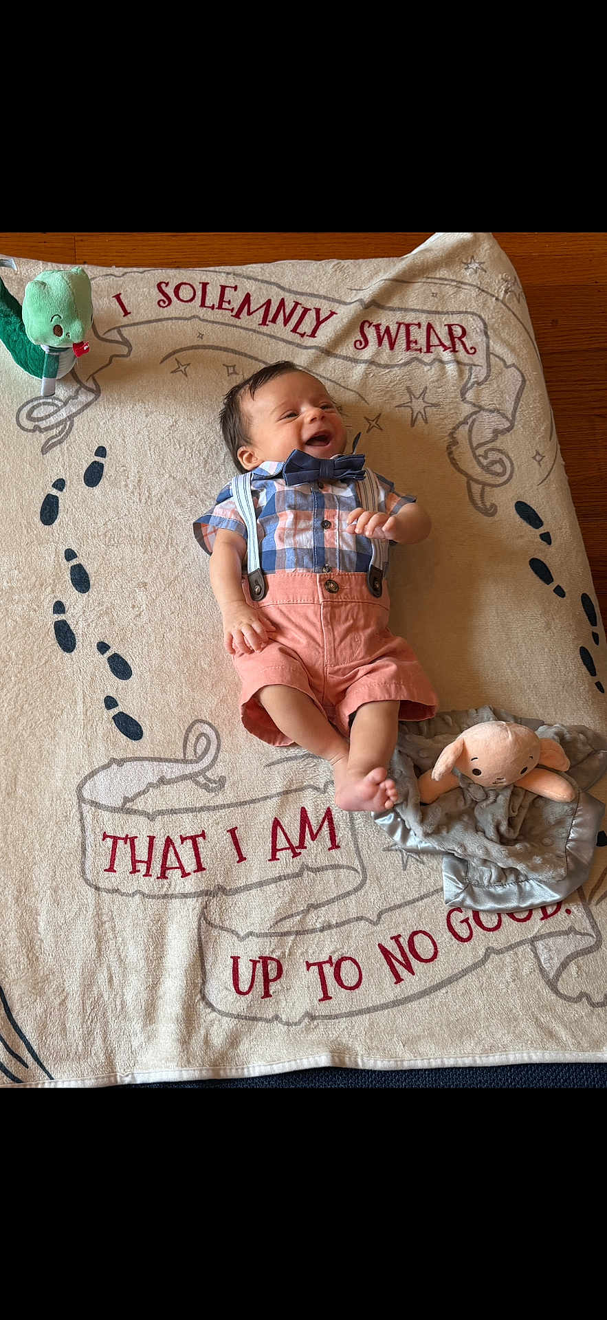 Antony Romeo is registered to the contest to win money with this photo: baby, infant, smiling, plush_toy, blanket, floor, wood_floor, child, clothing, bow_tie, suspenders, toy, soft_toy, cute, lying_down, happy, face, footwear, indoors, playful