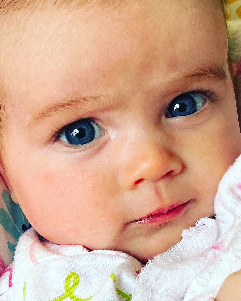 Audrey is registered to the contest to win money with this photo: baby, close_up, blue_eyes, face, infant, skin, soft_texture, clothing, white_garment, patterned_clothing, cute, innocence, portrait, child, young, expression, human, eye_contact, natural_light, adorable