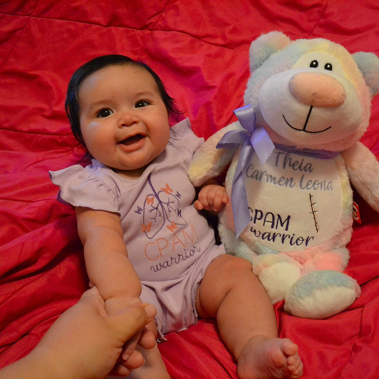 Theia is registered to the contest to win money with this photo: baby, bed, blanket, bodypart, couch, cushion, face, finger, furniture, hand, head, homedecor, indoors, person, photography, plush, portrait, sitting, teddybear, toy