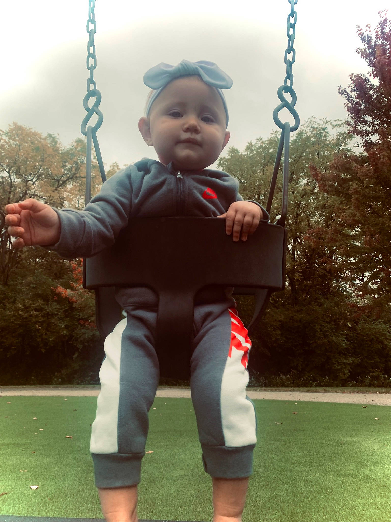 Amiya is registered to the contest to win money with this photo: baby, baby_toddler_clothing, child, fun, gesture, grass, happy, leisure, outdoor_play_equipment, person, playground, recreation, shoulder, sky, sleeve, standing, swing, t_shirt, toddler, tree
