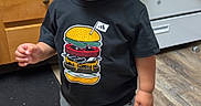 Sebastian is registered to the contest to win money with this photo: black_shirt, boy, burger_shirt, cabinets, child, full_body, happy, home, indoors, jeans, kitchen, oven, photograph, portrait, short_hair, smiling, sneakers, standing, toddler, wooden_floor
