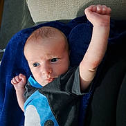 Elick joined the competition — help win amazing prizes! baby, infant, face, arm, blue_blanket, couch, clothing, person, skin, expression, fist, indoor, young_child, portrait, cute, lying_down, determined, head, eyes, toddler