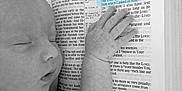 Elick is registered to the contest to win money with this photo: baby, sleeping, hand, bible, book, text, highlight, black_and_white, peaceful, infant, bedtime, religion, scripture, closeup, portrait, child, soft, blanket, clothing, faith