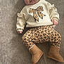Ariella is registered to the contest to win money with this photo: baby, infant, child, lying_down, sweater, leopard_print, pants, boots, cozy, cute, face, expression, indoor, floor, texture, clothing, person, portrait, warm, comfortable