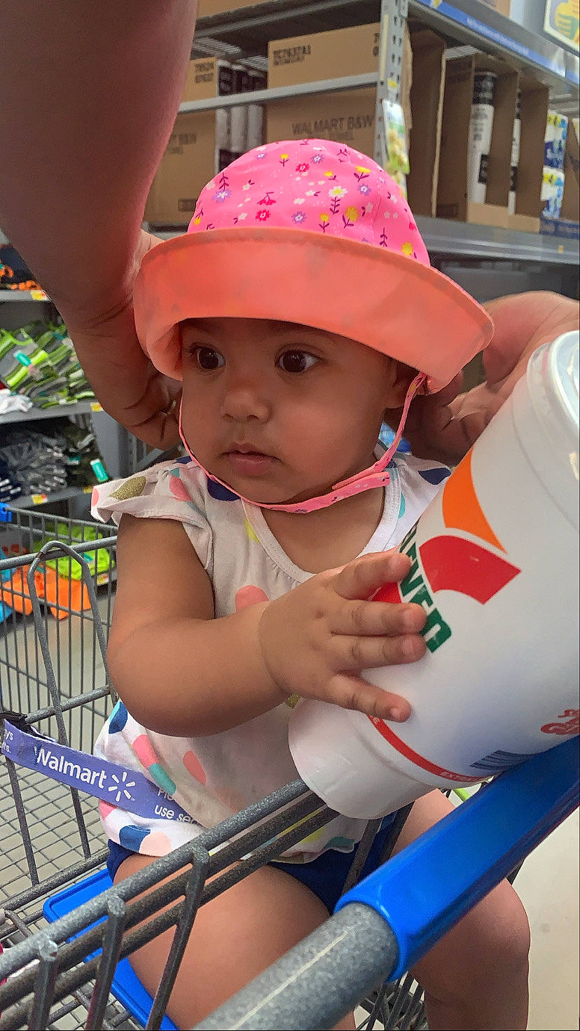 Dolores is registered to the contest to win money with this photo: baby, blue, cap, child, event, facial_expression, fun, happy, hat, headwear, human, leisure, person, pink, product, recreation, skin, summer, sun_hat, toddler