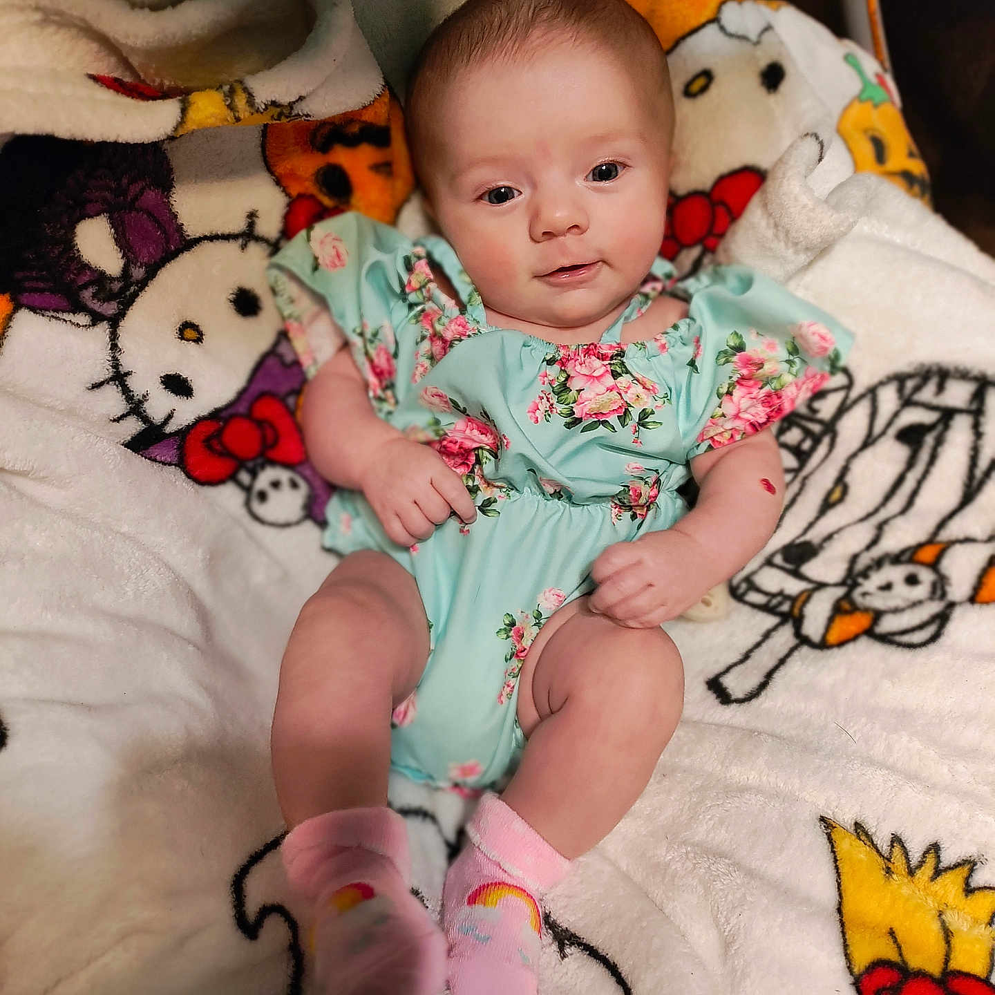 Zanna is registered to the contest to win money with this photo: baby, blanket, cartoon_characters, child, colorful, comfort, cute, cute_baby, face, floral_outfit, happy, indoor, infant, pink_socks, portrait, relaxed, skin, smiling, soft_texture, young
