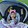 Kassandra is registered to the contest to win money with this photo: baby, stroller, blanket, pink_bow, headband, grass, outdoor, smiling, infant, child, seatbelt, white_shirt, sunlight, cute, portrait, young_child, baby_girl, comfort, baby_car_seat, happy