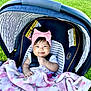 baby, car_seat, blanket, pink_bow, headband, smiling, outdoor, grass, child, infant, happy, seatbelt, striped_pattern, clothing, cute, portrait, young_child, sunlight, baby_girl, soft_texture